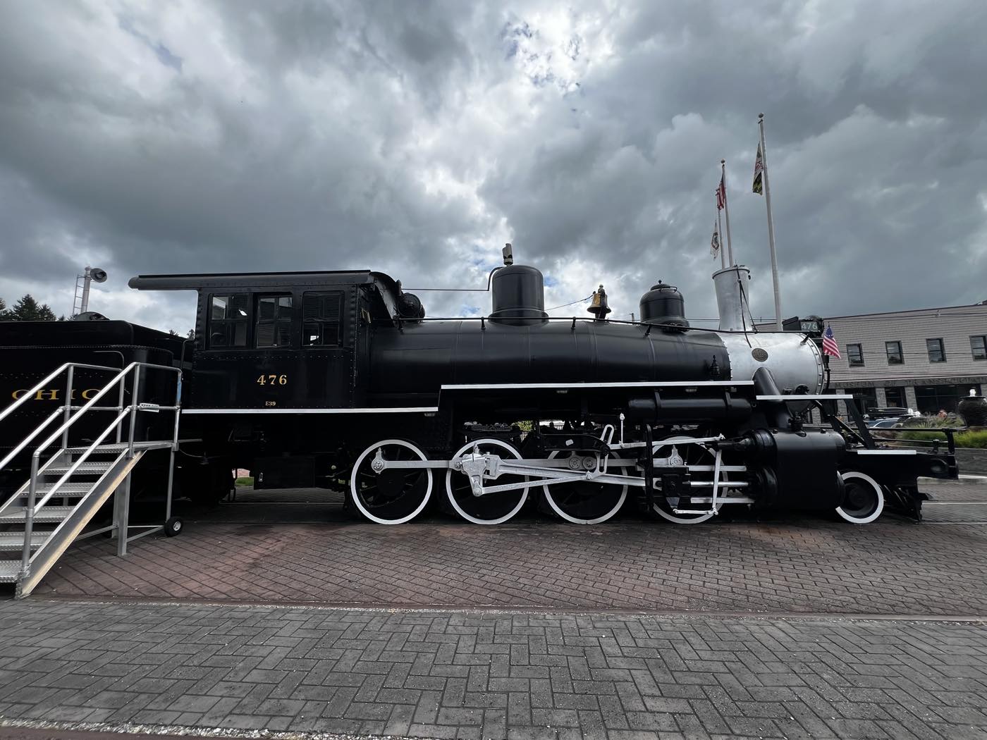 The same locomotive side-on, showing the cab, boiler and running gear, with a viewing platform and steps alongside.